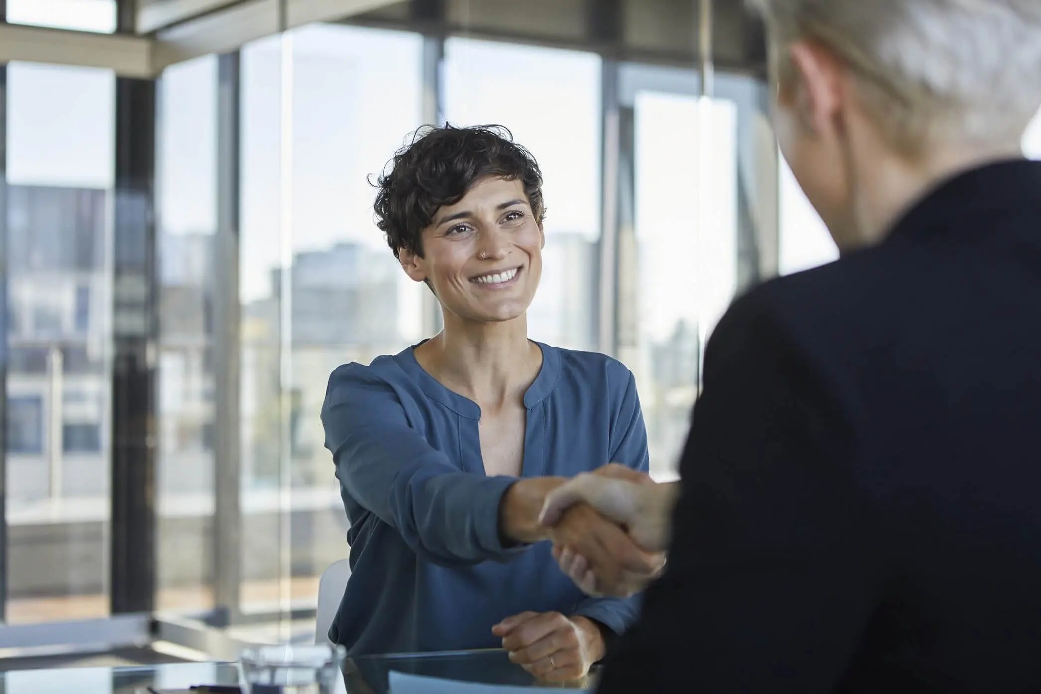 Two people shaking hands in office.
