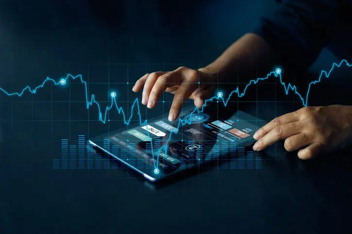 Hands interacting with a digital tablet displaying financial data and graphs.
