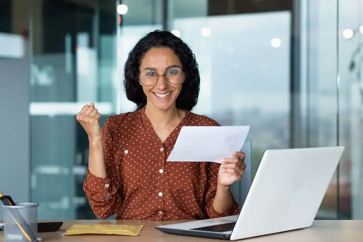 Woman happily reading a letter at her desk.