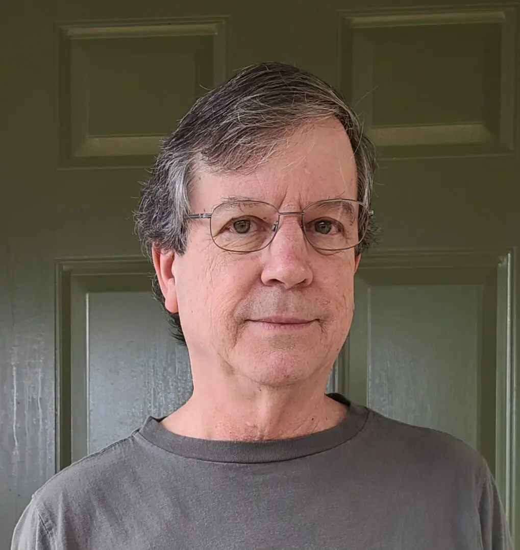 Portrait of a middle-aged man with glasses in front of a green door.